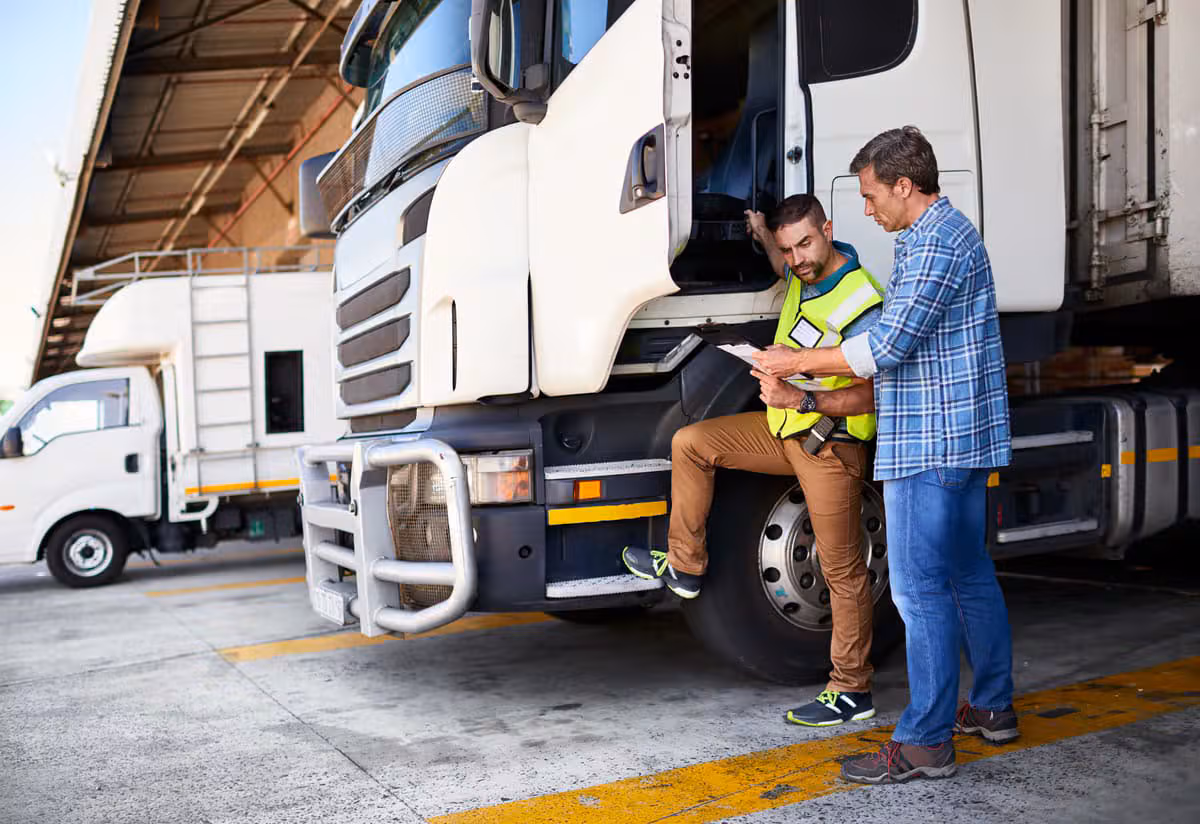 Two logistics professionals inspecting a truck at a warehouse